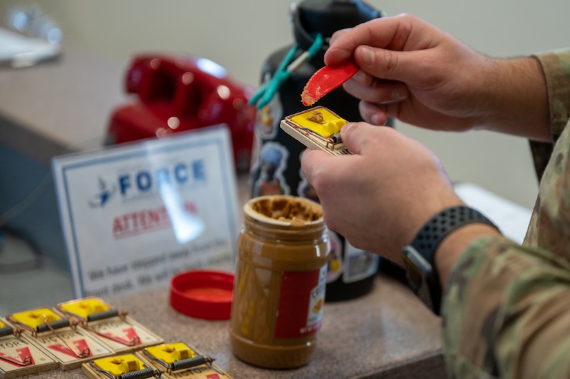 U.S. Air Force Senior Airman Christopher Cauldwell, 633d Civil Engineer Squadron pest management journeyman, baits a mouse trap at Joint Base Langley-Eustis, Dec. 4, 2023. The objective is to entice mice into the traps effectively, ensuring a successful capture and resolution of the pest issue. (U.S. Air Force photo by Airman 1st Class Skylar Ellis)