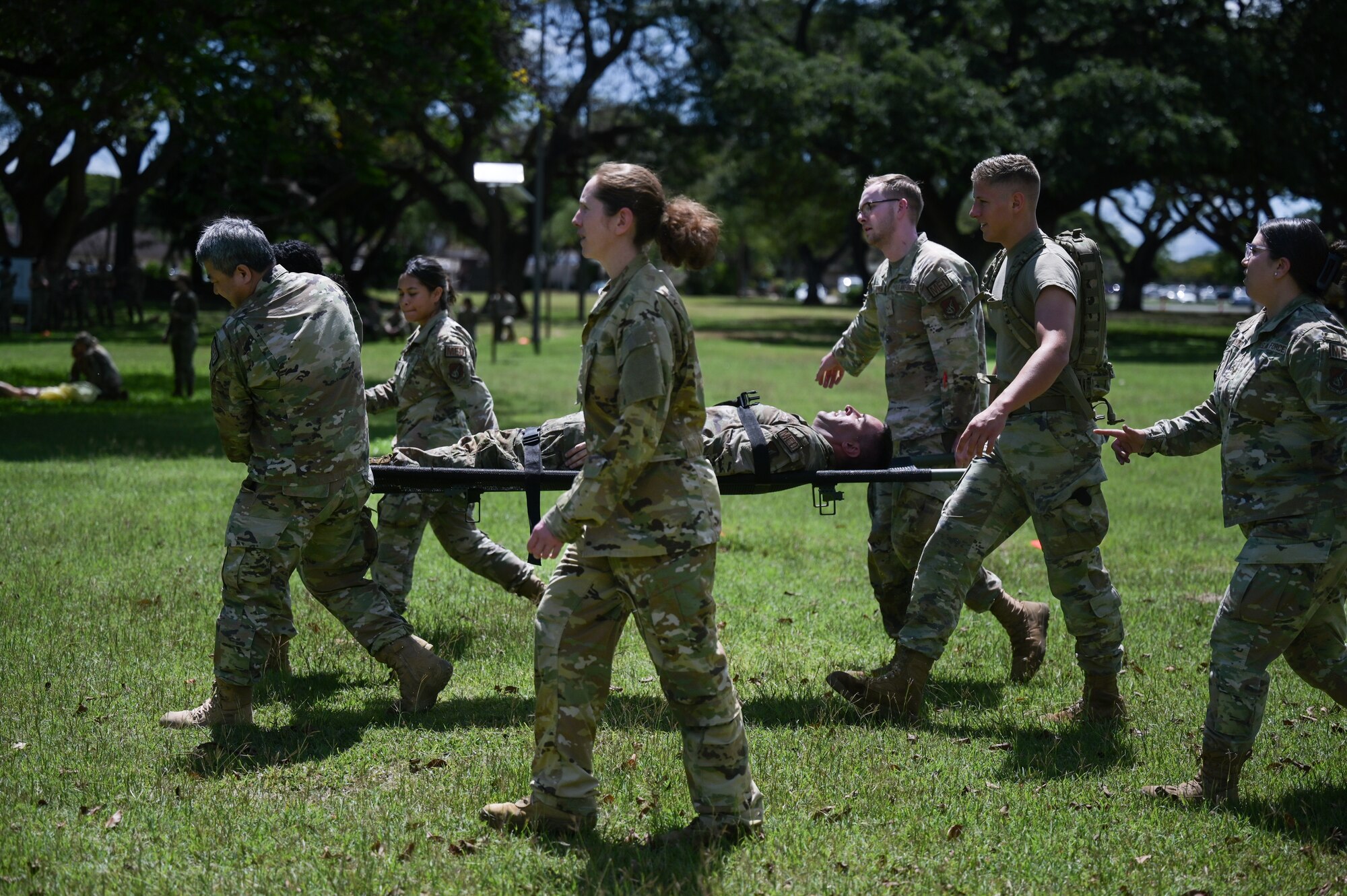 Airmen perform a litter carry in a field.