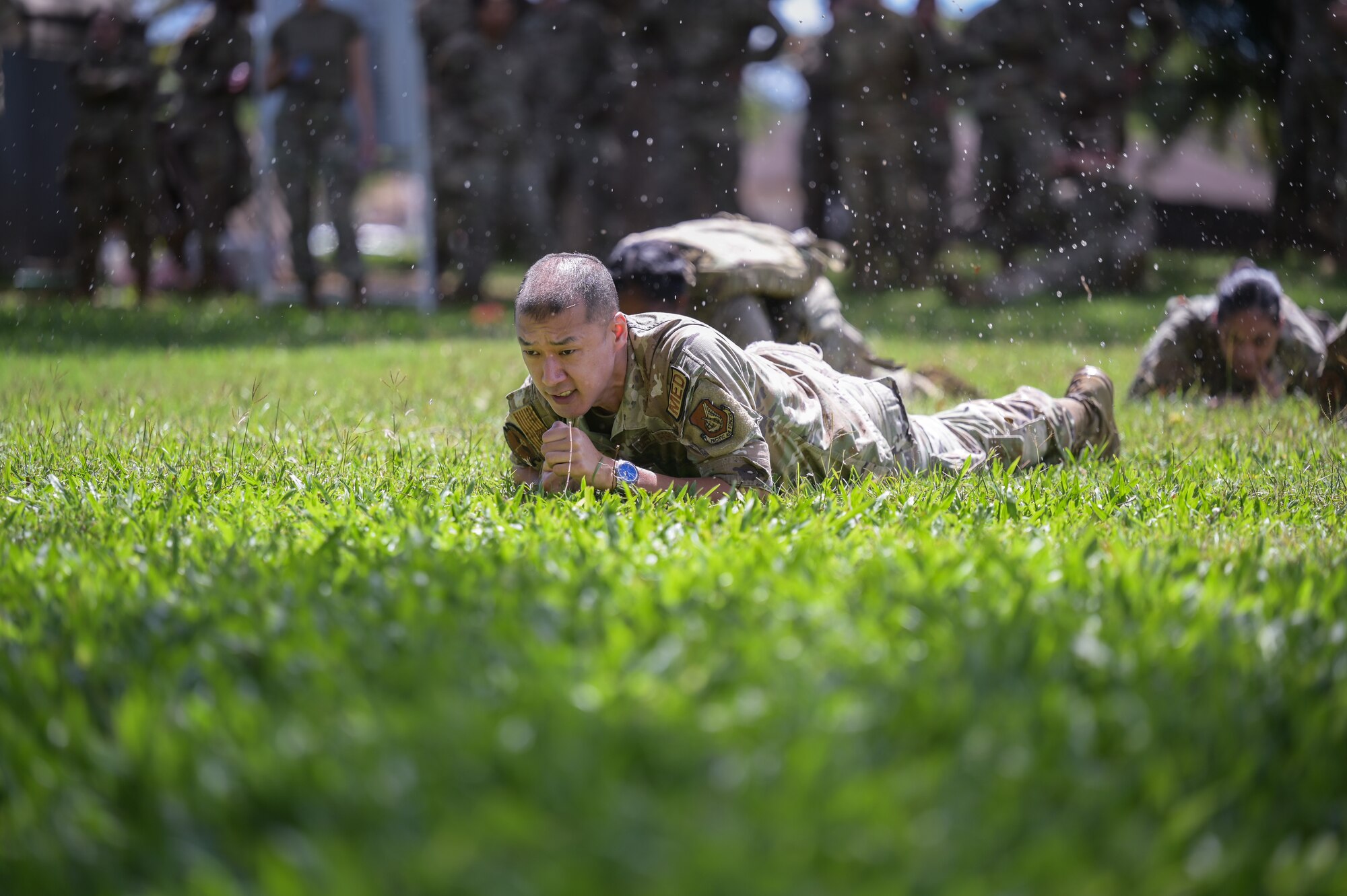 Maj. Michael Hsu, 15th Healthcare Operations Squadron operations officer, performs a low crawl during a Tactical Combat Casualty Care and Ability to Survive and Operate relay at Joint Base Pearl Harbor-Hickam, Hawaii, April 17, 2024. Medics were placed in a simulated care under-fire situation while showcasing TCCC during the relay. (U.S. Air Force photo by Staff Sgt. Alan Ricker)