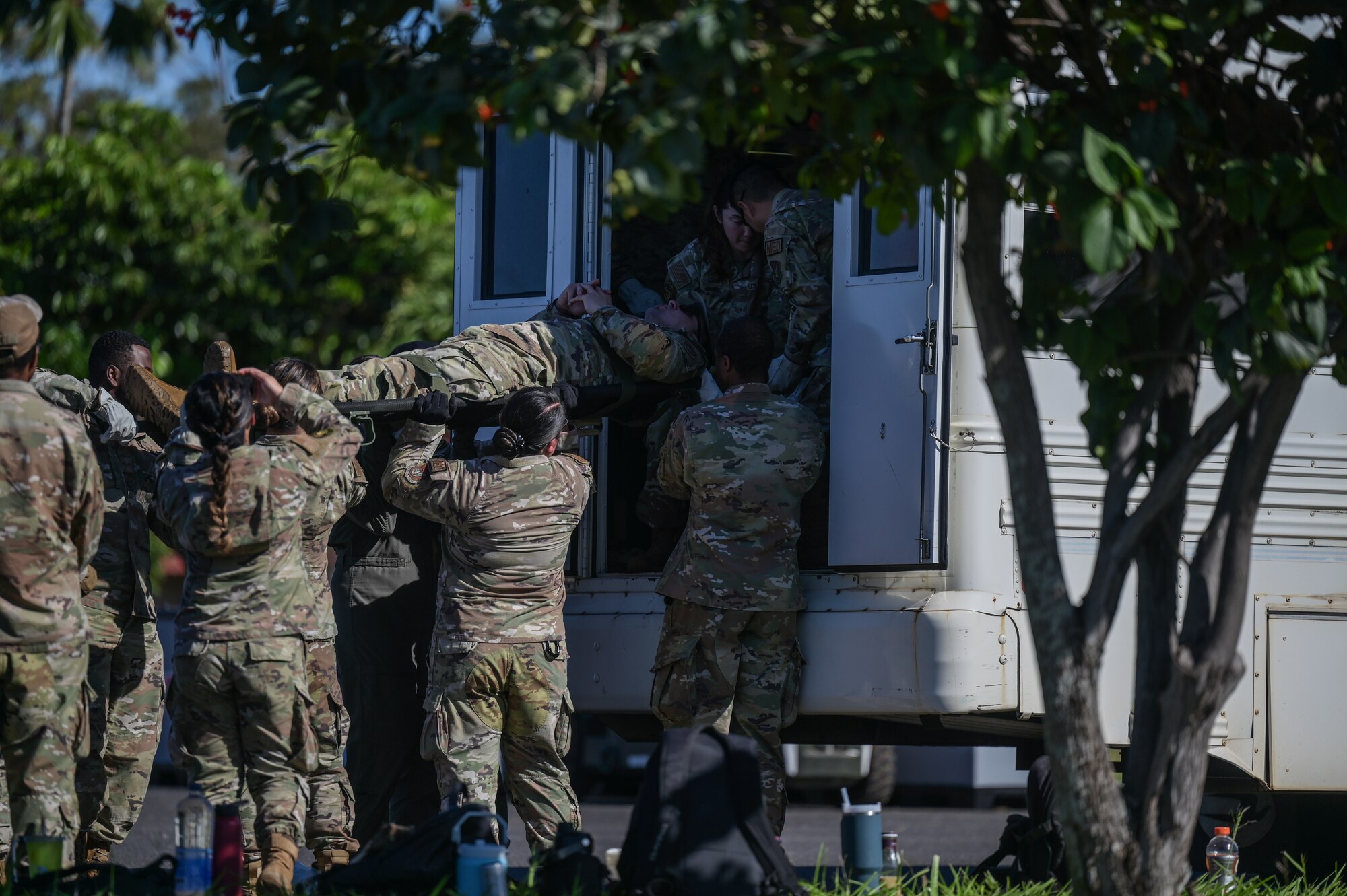 Airmen move simulated patient into medical bus.
