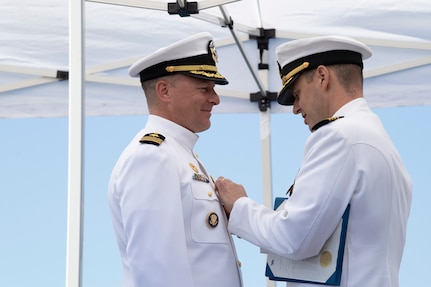 Capt. Gary Montalvo, commander, Submarine Development Squadron (DEVRON) 5, awards the Meritorious Service Medal to Cmdr. Jeffrey Fassbender, outgoing commanding officer of the Seawolf-class fast-attack submarine USS Seawolf (SSN 21) at a change of command ceremony held at Naval Base Kitsap-Bangor in Silverdale, Washington, May 16, 2023. During the ceremony, Fassbender was relieved by Cmdr. Douglas Hagenbuch. (U.S. Navy photo by Mass Communication Specialist Seaman Sophia H. Bumps)