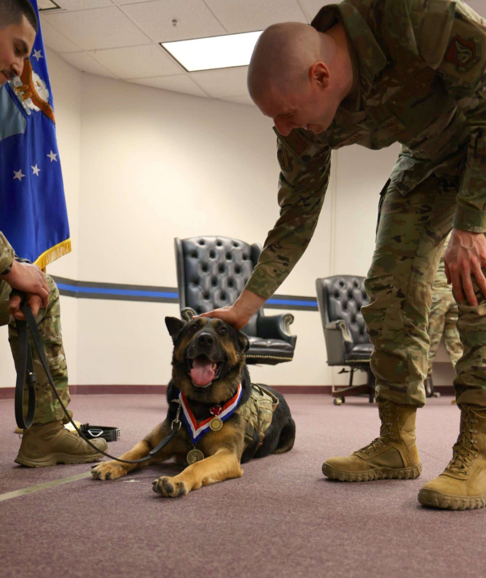Chief Master Sgt. Sean Miligan pets MWD Jocky.