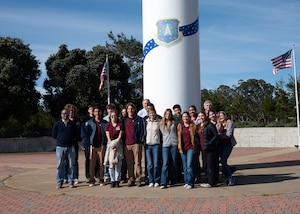 Group of students pose for a group photo in front of a missile static display.