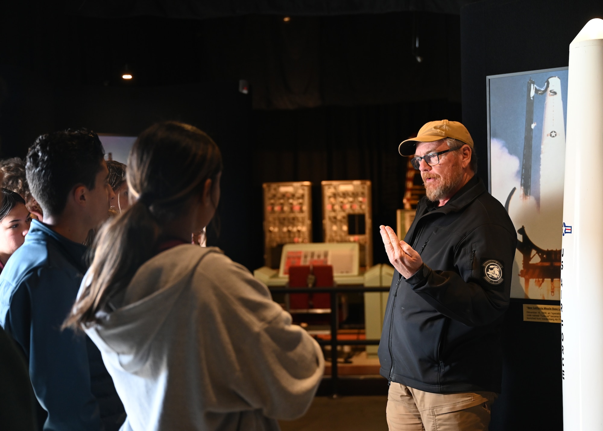 Man speaks to a group of students in museum.