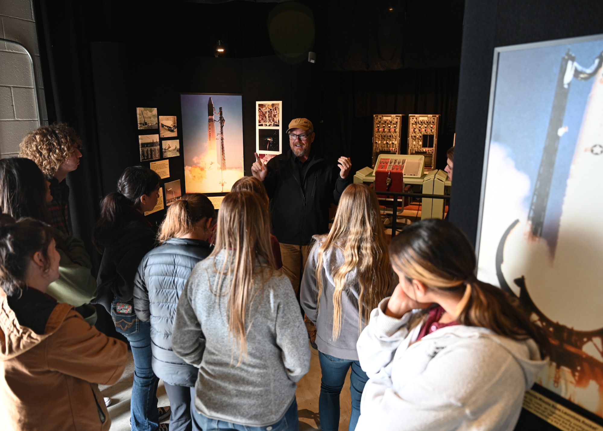Man speaks to a group of students in museum.