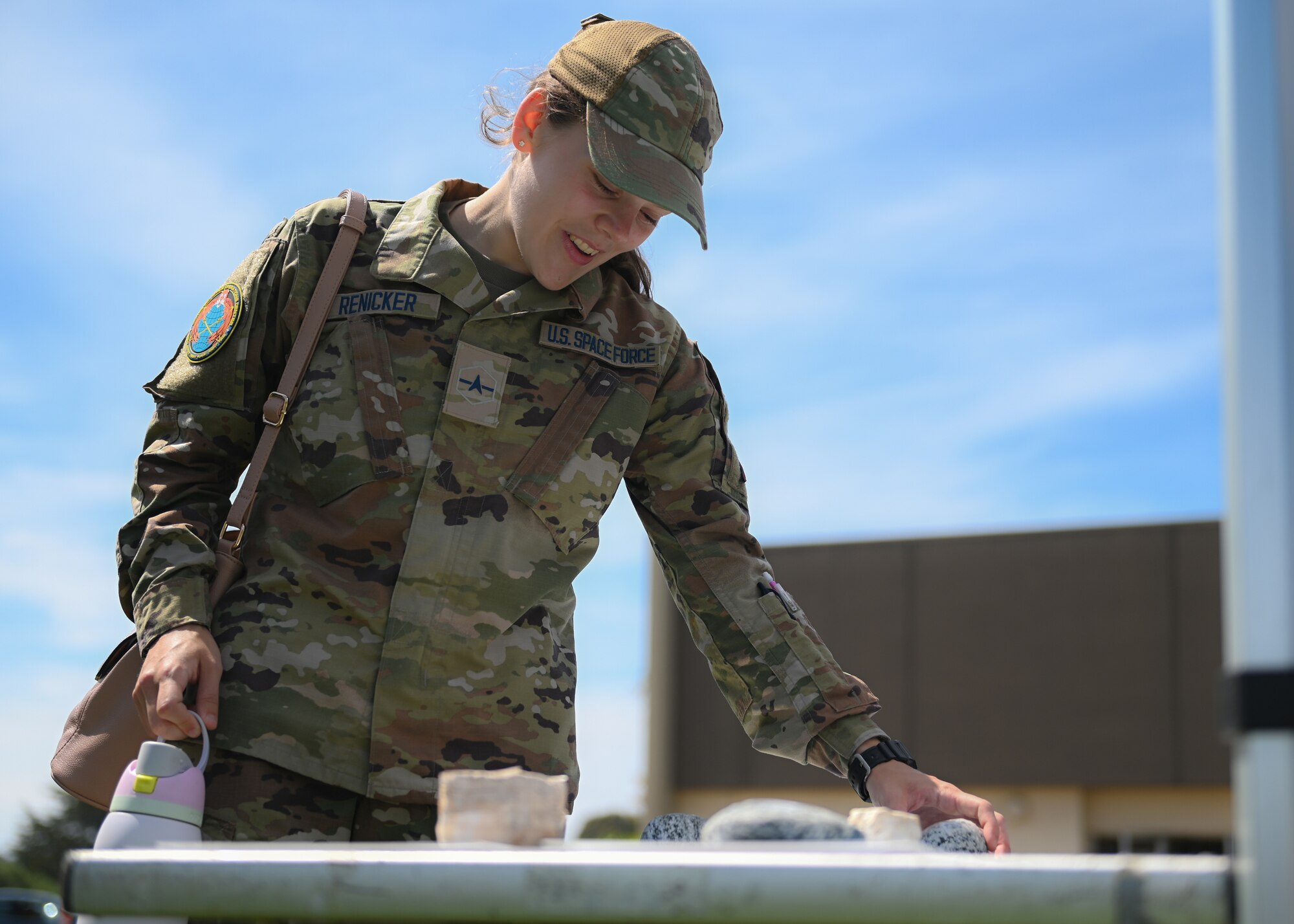 A women interacts with rocks on a table outside.