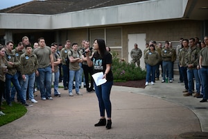 A women speaks into a microphone in front of a crowd of students.