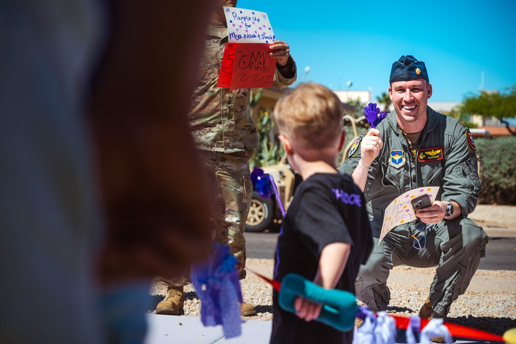U.S. Air Force Maj. Christopher Kirk, 61st Fighter Squadron pilot, waves to his son during a Purple Up parade.
