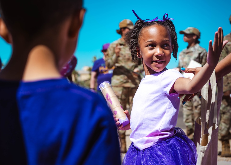 A child from the Luke Air Force Base Child Development Center blows a kiss to her mother during a Purple Up parade