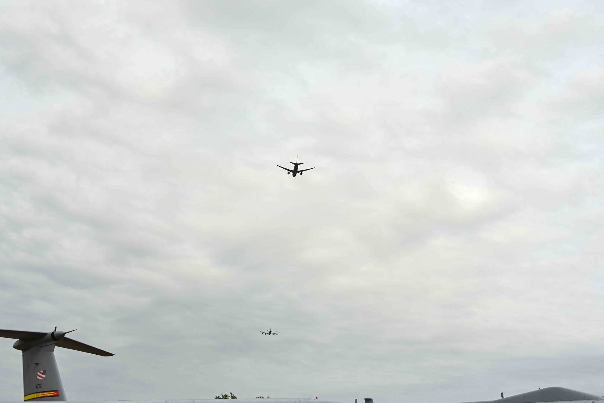 A KC-135 Stratotanker aircraft and a KC-46 Pegasus aircraft execute a flyover during the Boom Operator Memorial at Altus Air Force Base, Oklahoma, April 19, 2024. The flyover occurred at the conclusion of the national anthem, while an honor guardsman played taps (U.S. Air Force photo by Airman 1st Class Kari Degraffenreed)