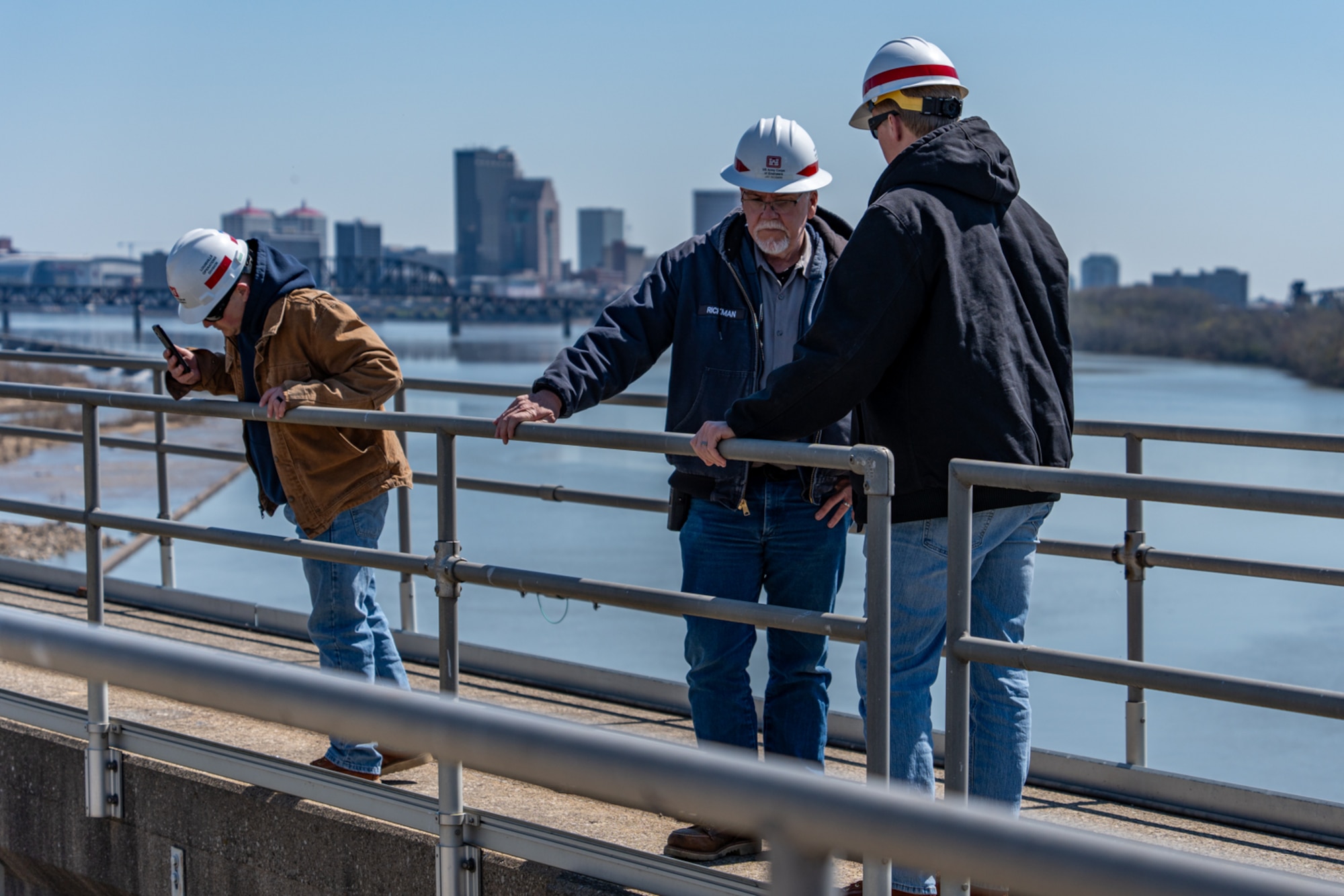 USACE Louisville District Locks and Dam Operations Manager Brad Stout (left), McAlpine Locks and Dam Lockmaster Jay Rickman and Locks and Dams Assistant Operations  Manager Davis Mattingly discuss the effects of barge hydrodynamics during offloading operations and the best procedure for safely removing the remaining coal, March 28.