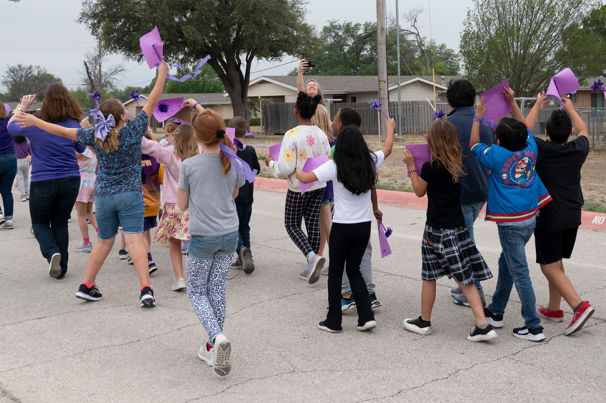 Tammy Davidson, Roberto “Bobby” Barrera (RBB) Elementary School educator, takes photos as RBB students walk the “Purple Up Parade” held at Laughlin Air Force Base, Texas, April 17, 2024. This parade was dedicated to celebrating Purple Up Day and Month of the Military Child, a time devoted to showing support and appreciation for the difficulties military children experience throughout their parent's military careers. (U.S. Air Force photo by Senior Airman Kailee Reynolds)