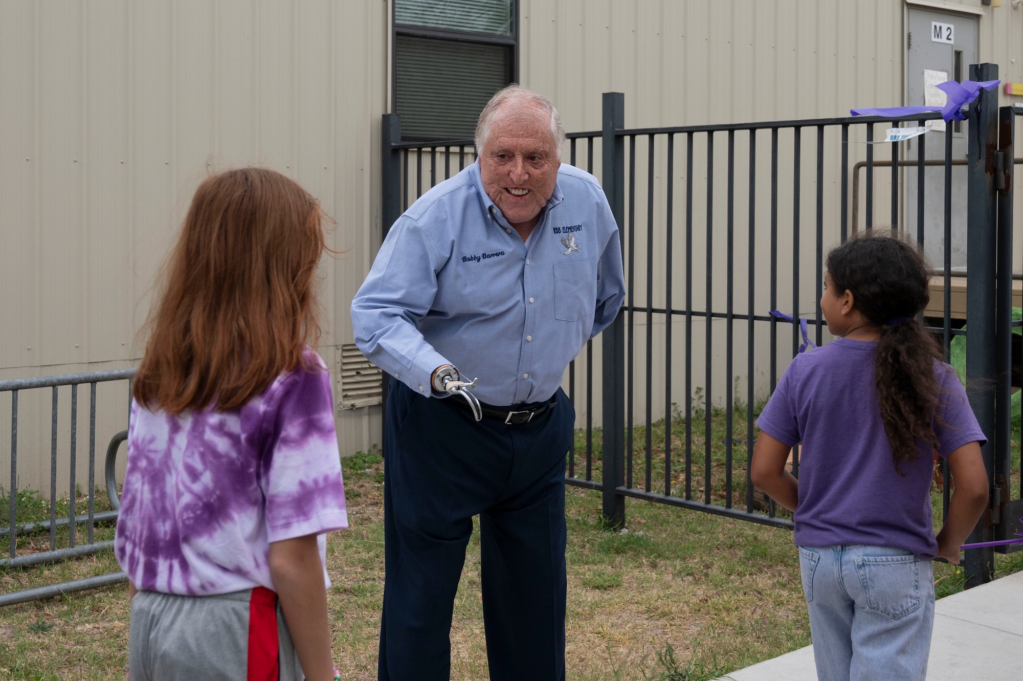 Roberto Barrera, U.S. Marine Corp. veteran and former educator, whom the school was named after, greets students entering the grounds of the Roberto “Bobby” Barrera (RBB) Elementary School during a “Purple Up Parade” event held at Laughlin Air Force Base, Texas, April 17, 2024. This parade celebrated Purple Up Day and Month of the Military Child, a time devoted to showing support and appreciation for military children. (U.S. Air Force photo by Senior Airman Kailee Reynolds)