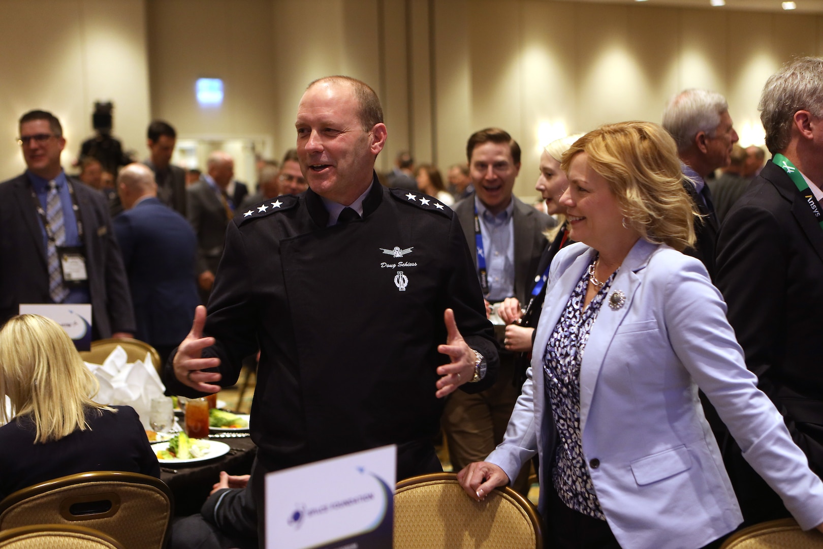 Man in uniform and woman stand next to each other smiling