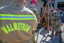 A team of firefighter lower a man in a manhole