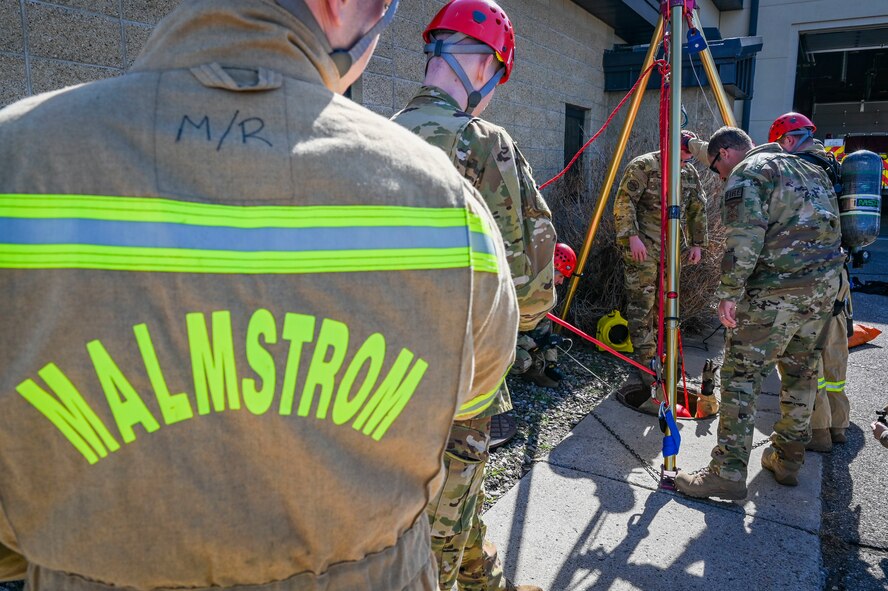 A team of firefighter lower a man in a manhole