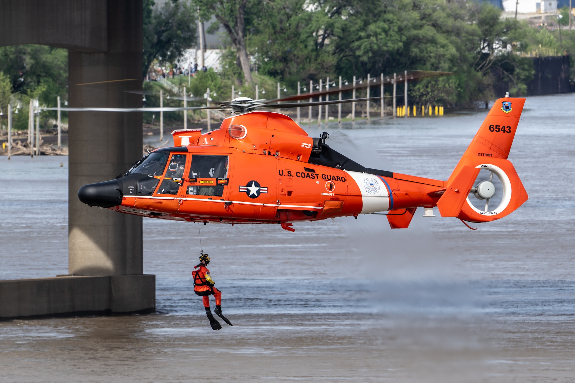 A U.S. Coast Guard rescue swimmer is lowered into the Ohio River as part of a helocast water-rescue demonstration during the Thunder Over Louisville air show in Louisville, Ky., April 20, 2024. This year’s event featured more than two-dozen military and civilian aircraft, including the Kentucky Air National Guard’s C130J Super Hercules. (U.S. Air National Guard photo by Dale Greer)
