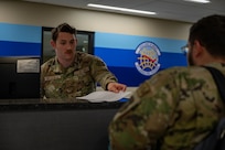 A photo of an Airman passing a paper to another Airman.