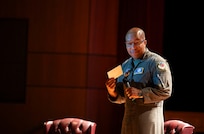 A photo of an Airman speaking on a stage.
