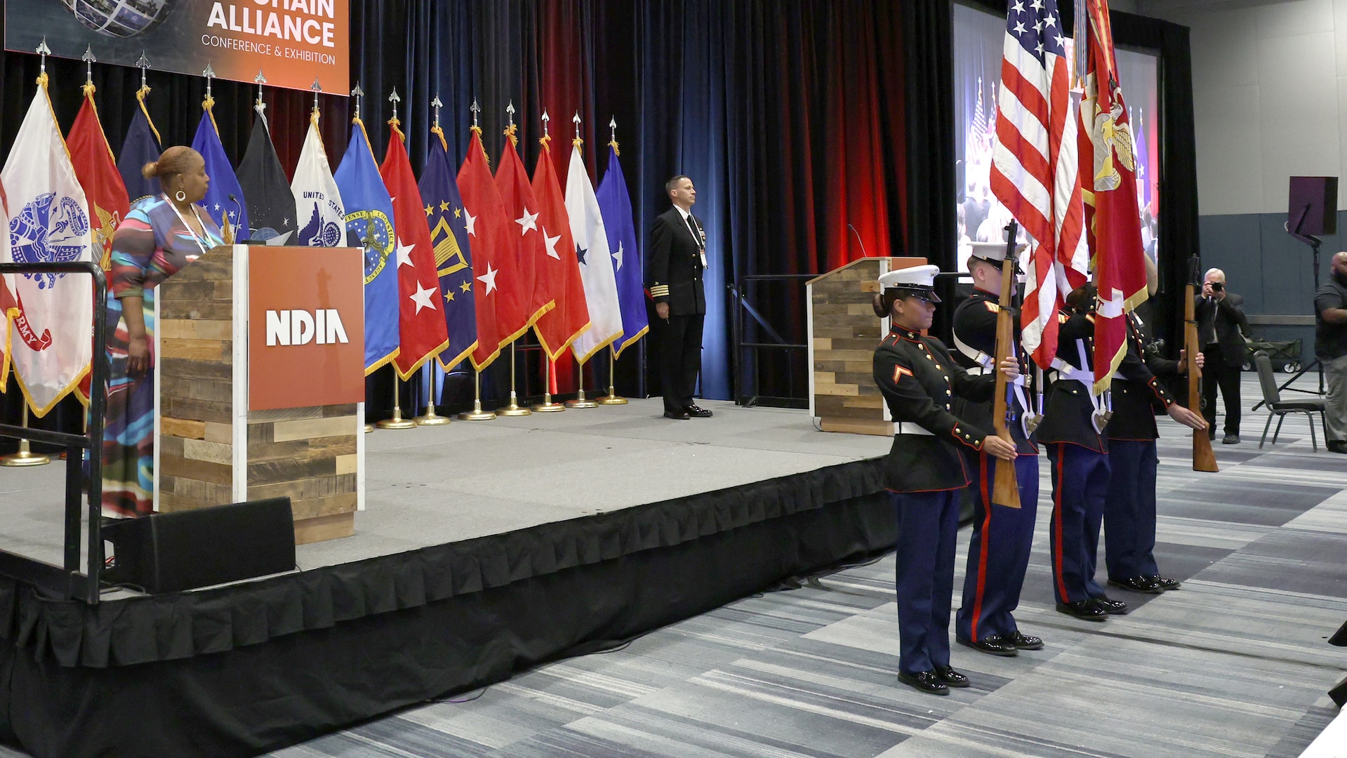 Marines present the colors and flags on stage behind.