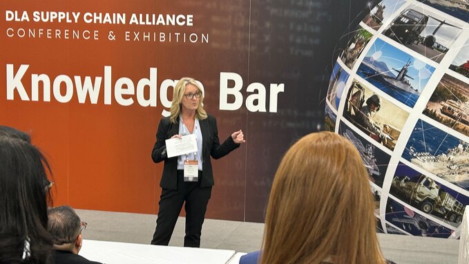 Woman in black suit and white shirt stands in front of Knowledge Bar sign.