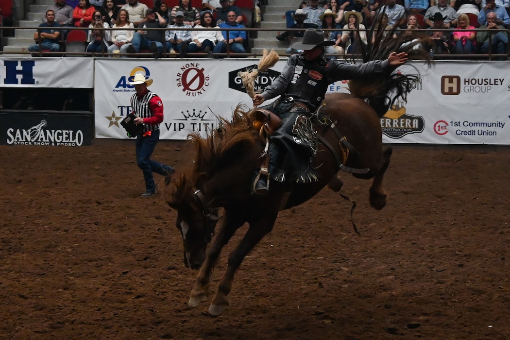 A saddle bronc rider competes during Military Appreciation Night at the San Angelo Stock Show & Rodeo at Foster Communications Coliseum in San Angelo, Texas, April 17, 2024. A saddle bronc rider’s score comes from how well they rode and how difficult the horse was to ride. (U.S. Air Force photo by Airman 1st Class Brian Lummus)