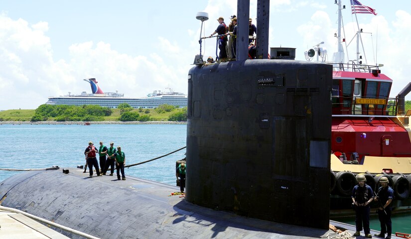 Sailors stand aboard a submarine.