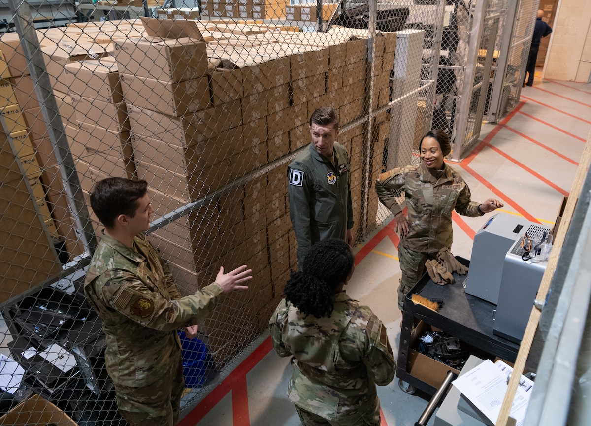 U.S. Air Force Senior Airman Chase Davies, left, and Senior Airman Danielle Turner, both 100th Communication Squadron information technology distribution technicians, explain how to properly destroy sensitive information storage media to the 100th Air Refueling Wing command team at Royal Air Force Mildenhall, England, April 19, 2024.