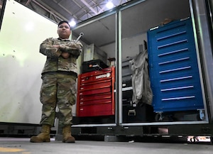 Senior Airman Kyle Adrian Mercurio, 9th Expeditionary Squadron weapons technician, poses for a photo in front of weapons back stock tools and materials in the maintenance hangar at Morón Air Base, Spain, during Bomber Task Force Europe April 22, 2024. Mercurio immigrated to the U.S. with his family in 2014 from the Philippines with hopes of a better quality of life and new opportunities. Now, he is using his drive and appreciation for the military, which was instilled in him by his father, to help complete the 9th EBS mission during BTF Europe. (U.S. Air Force photo by Staff Sgt. Holly Cook)