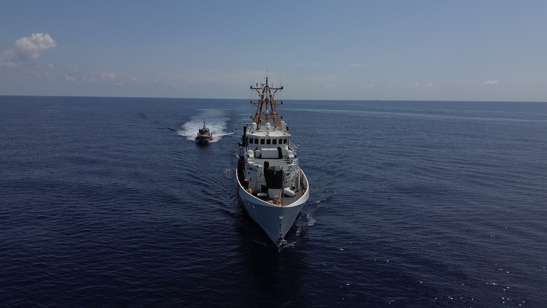 The Coast Guard Cutter Willow sails through the water. Parallel to the Willow, the Coast Guard Cutter Isaac Mayo sails alongside.