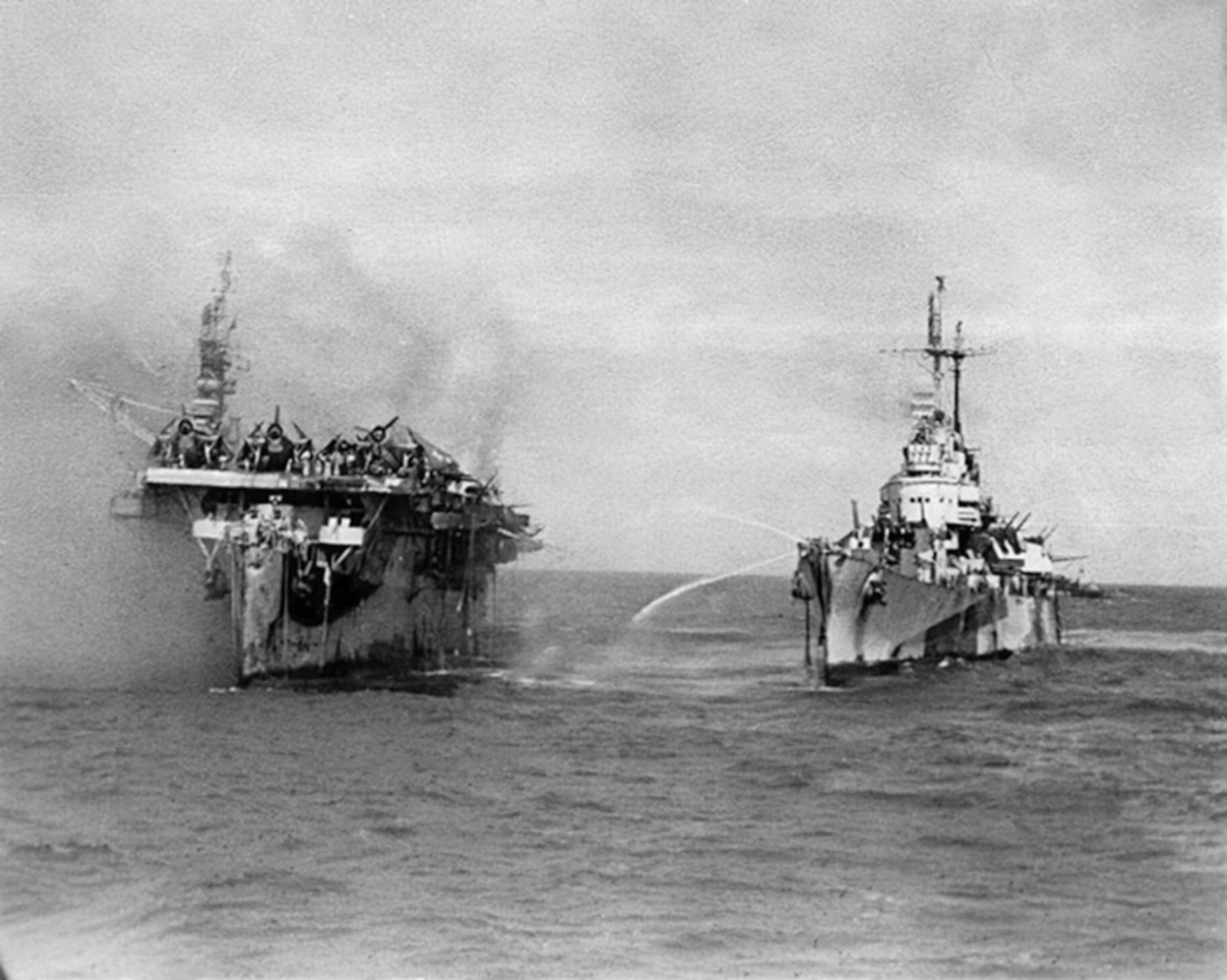 Battle of Leyte Gulf, October 1944. USS Birmingham (CL-62) comes alongside the burning USS Princeton (CVL-23) to assist with fire fighting, 24 October 1944. Official U.S. Navy Photograph, now in the collections of the National Archives.