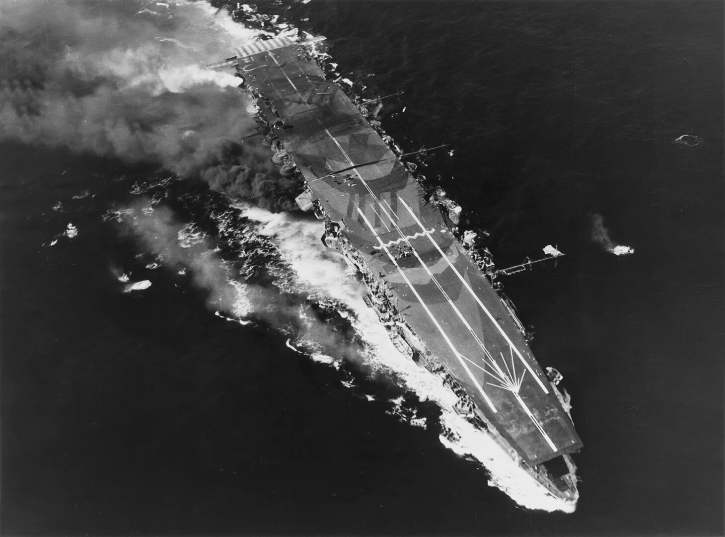 Battle of Leyte Gulf, October 1944. Japanese aircraft carrier ZUIHO still underway after several hits by planes from task force 38 during the battle off Cape Engano, 25 October 1944. Photographed from a USS ENTERPRISE (CV-6) aircraft. Note flight deck camouflage, men on deck, buckled flight deck amidships and mast deployed horizontally, with a Japanese Naval ensign at its tip.