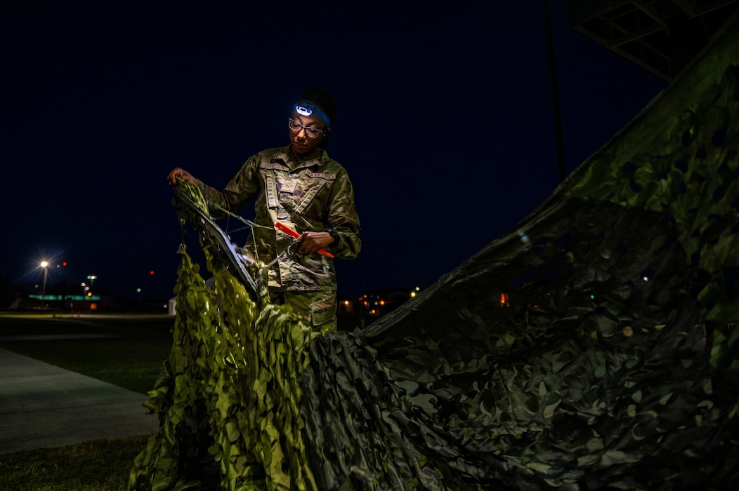 U.S. Air Force Airman 1st Class Samera Epperson, 23rd Communications Squadron tactical radio technician unwraps a tactical camouflage netting during Exercise Ready Tiger 24-1 at Savannah Air National Guard Base, Georgia, April 14, 2024. Airmen responded to an exercise scenario that required communications to be recalibrated at night. During Ready Tiger 24-1, exercise inspectors will assess the 23rd Wing's proficiency in employing decentralized command and control to fulfill air tasking orders across geographically dispersed areas amid communication challenges, integrating Agile Combat Employment principles such as integrated combat turns, forward aerial refueling points, multi-capable Airmen, and combat search and rescue capabilities. (U.S. Air Force photo by Senior Airman Courtney Sebastianelli)