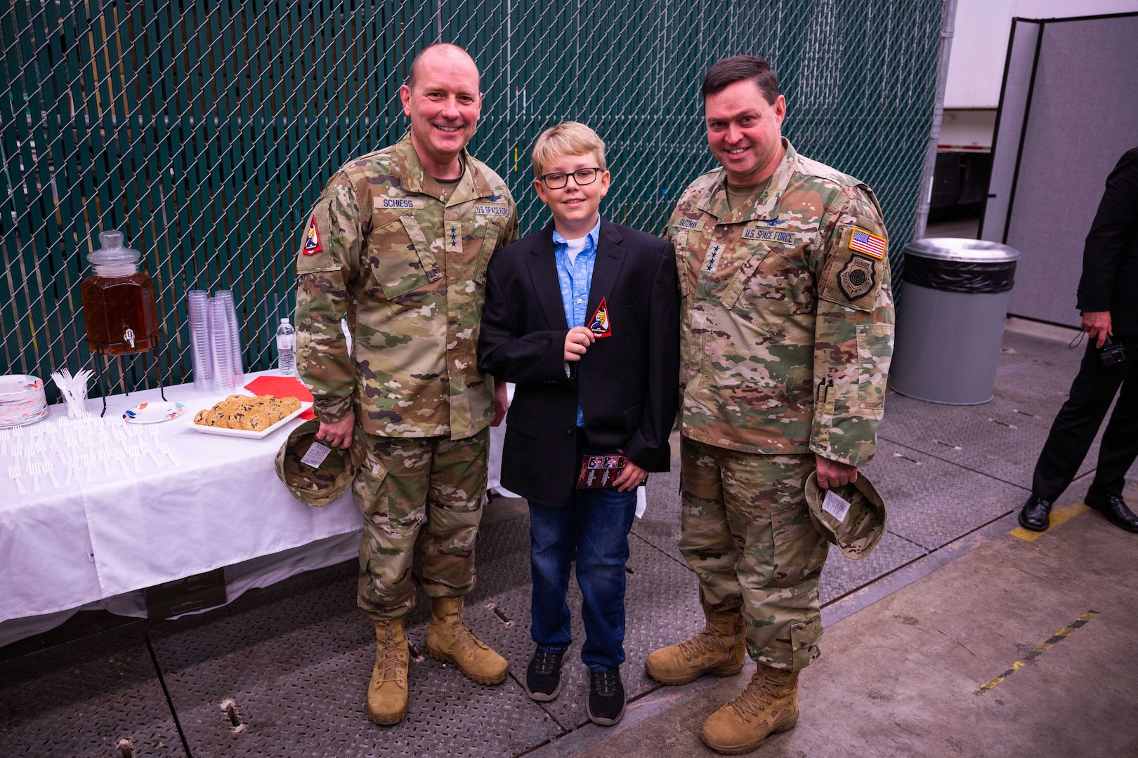U.S. Space Force Lt. Gen. Douglas A. Schiess, S4S commander and the Combined Joint Force Space Component Commander, left, and U.S. Space Forces Chief of Space Operations Gen. B. Chance Saltzman, right, congratulate 12-year-old Asher L. Paulson on his contributions to the design elements of the S4S emblem after the S4S activation ceremony at Vandenberg Space Force Base, Calif., Jan. 31, 2024. Asher, son of U.S. Air Force Maj. William Paulson, S4S Deputy Staff Judge Advocate, is credited with the original creation of the tiger used in the S4S emblem and integral to the design being ready by activation. (U.S. Space Force photo by Tech. Sgt. Luke Kitterman)