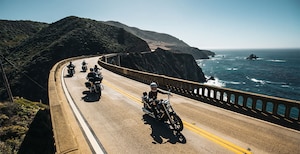 Photo with 4 motorcycle riders driving down a road along the California coast.
