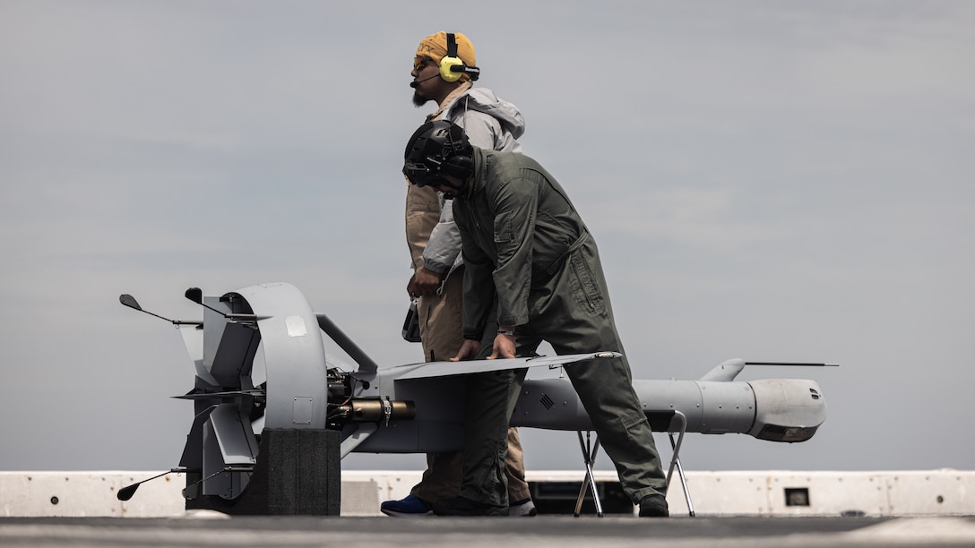 Civilian contractors in support of the 24th Marine Expeditionary Unit (MEU) conduct pre-flight checks on a V-BAT unmanned aircraft system aboard USS New York (LPD 21) while underway in the Atlantic Ocean during Composite Unit Training Exercise (COMPTUEX), April 17, 2024. The Wasp (WSP) Amphibious Ready Group (ARG)-24th MEU is conducting COMPTUEX, their final at-sea, certification exercise under the evaluation of Carrier Strike Group 4 and Expeditionary Operations Training Group. Throughout COMPTUEX, the WSP ARG-24th MEU is evaluated across a spectrum of scenarios that determine their readiness to deploy. (U.S. Marine Corps photo by Lance Cpl. Ryan Ramsammy)