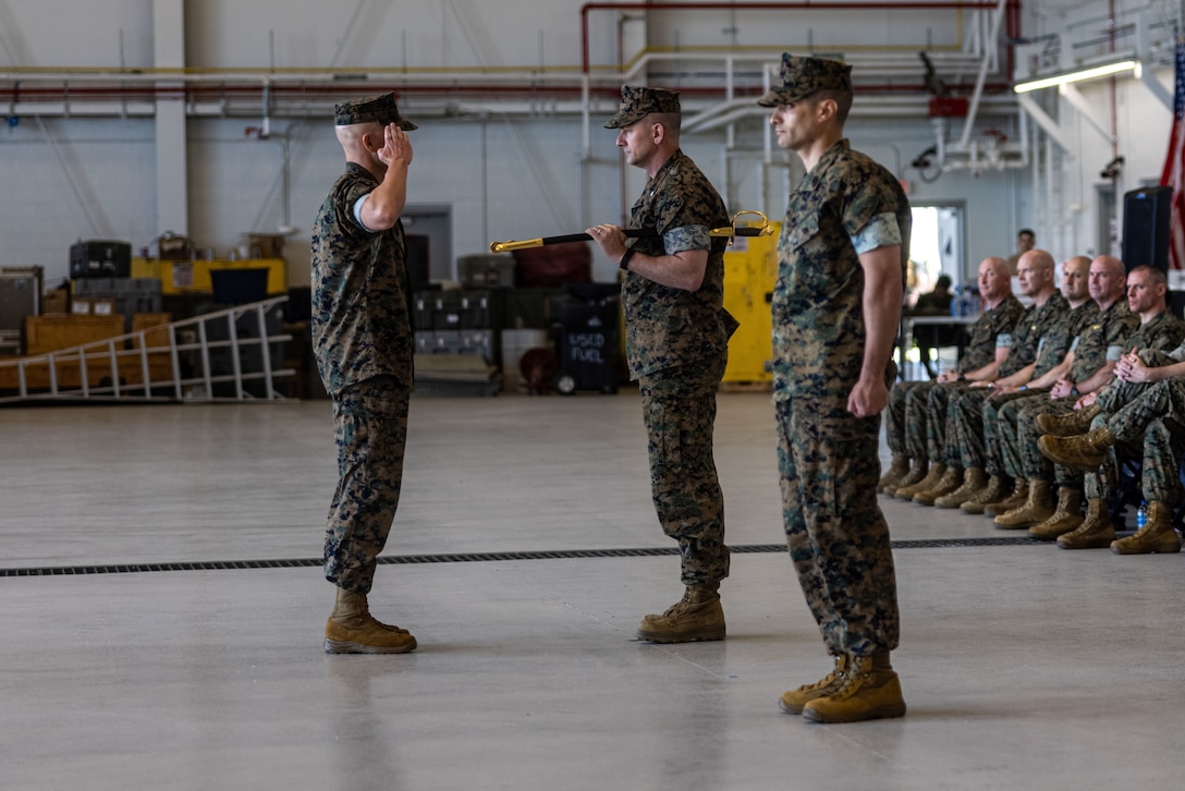 U.S. Marine Corps Lt. Col. Larry L. Buzzard (center), the commanding officer for Marine Medium Tiltrotor Squadron (VMM) 162 (Reinforced), 26th Marine Expeditionary Unit (Special Operations Capable) (MEU(SOC)), prepares to appoint Sgt. Maj. Sean Blue (left) as the Sergeant Major of VMM-162 (Rein.) during a relief and appointment ceremony at Marine Corps Air Station New River, North Carolina, Apr. 18, 2024. The relief and appointment ceremony serves as the official changeover between Sergeants Major, honoring the outgoing Sergeant’s Major contributions during his tenure and allowing the oncoming SgtMaj to introduce himself to the Marines now under his charge. (U.S. Marine Corps photo by Cpl. Rafael Brambila-Pelayo)