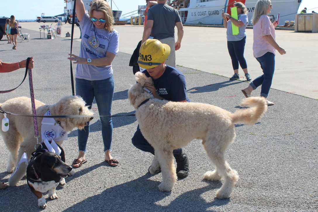 Petty Officer 3rd Class Jackson Hart, a boatswain's mate assigned to U.S. Coast Guard Cutter Dauntless (WMEC 624), greets his family's dogs after Dauntless returned home from deployment, April 24, 2024, in Pensacola, Florida. Dauntless deployed for two months to support Operation Vigilant Sentry while conducting maritime safety and security missions. (U.S. Coast Guard photo by Lt.j.g. Olivia Gonzalez)