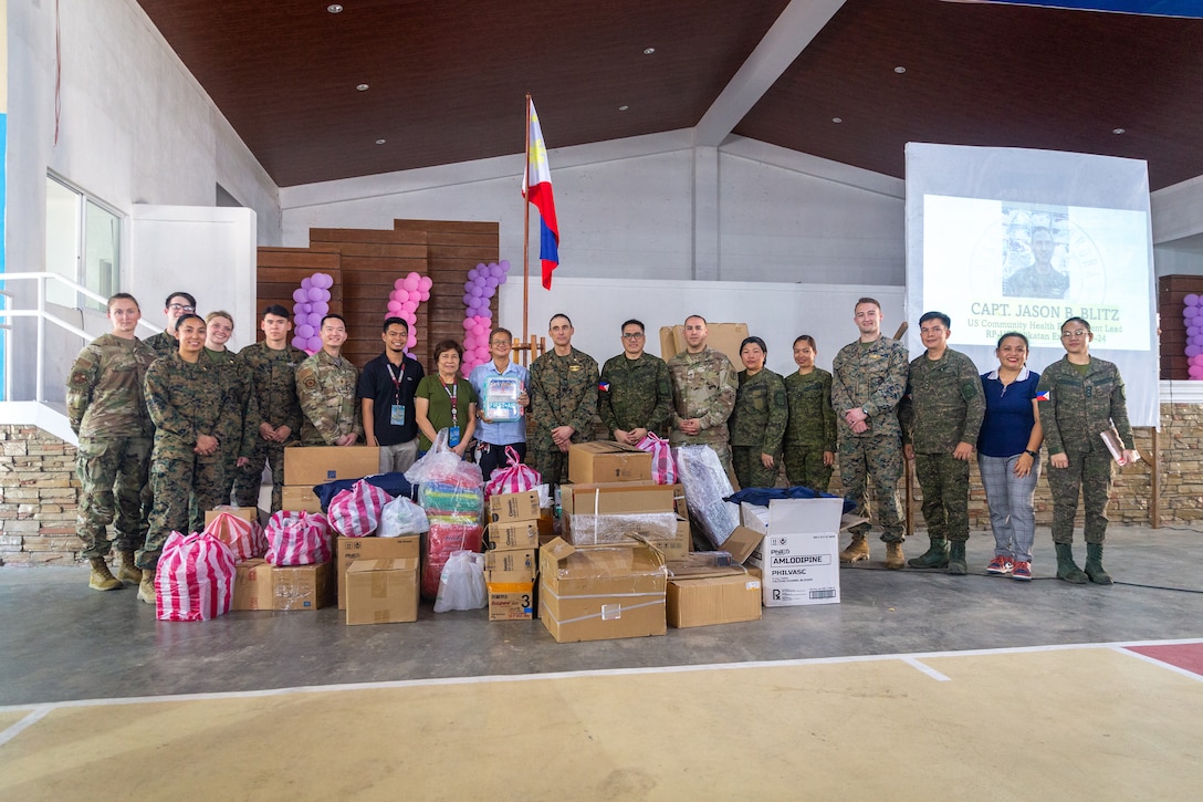 Philippine and U.S. service members with the Combined Joint Civil-Military Operations Task Force, alongside members of the community, pose for a photograph behind donated medical, dental, and office supplies during a community health engagement held before Exercise Balikatan 24 at the Dingalan Municipal Gymnasium in Dingalan, Aurora, Philippines, April 5, 2024. The donated supplies included pallets of medicine, mosquito nettings, dental tools, a CPR mannequin, and more. BK 24 is an annual exercise between the Armed Forces of the Philippines and the U.S. military designed to strengthen bilateral interoperability, capabilities, trust, and cooperation built over decades of shared experiences. (U.S. Marine Corps photo by Cpl. Trent A. Henry)