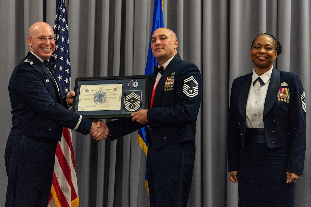 U.S. Air Force Col. Chris McDonald, left, 436th Airlift Wing commander, and U.S. Air Force Chief Master Sgt. Carolyn Russell, right, 436th AW command chief, present U.S. Air Force Senior Master Sgt. Christian Ruiz, 436th Aerial Port Squadron air freight superintendent, with a plaque signifying his selection to chief master sergeant at Dover Air Force Base, Delaware, April 19, 2024. Ruiz was one of 506 Airmen selected for promotion to the top enlisted rank of chief for the 23E9 promotion cycle. (U.S. Air Force photo by Roland Balik)