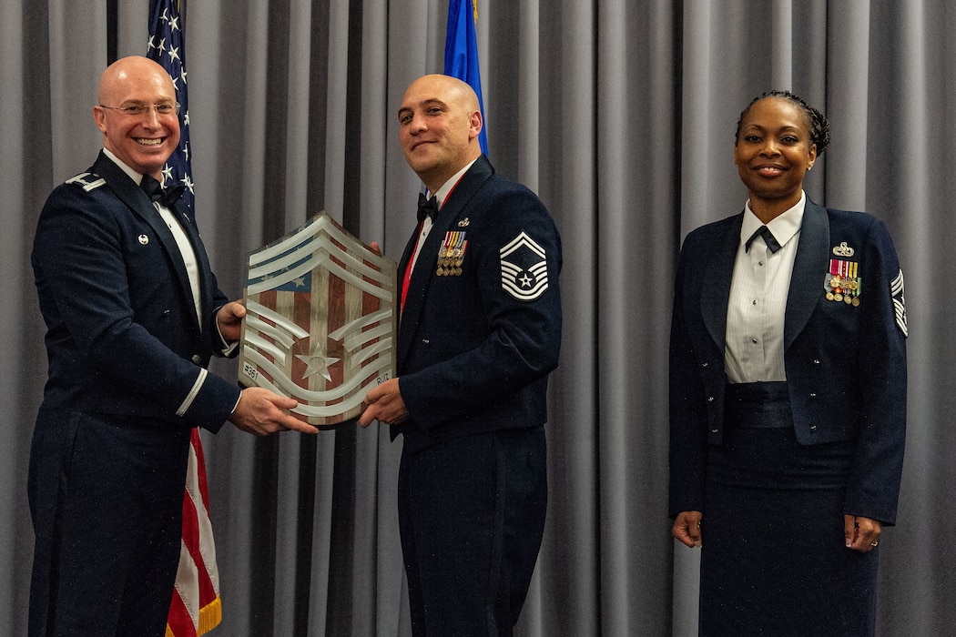 U.S. Air Force Col. Chris McDonald, left, 436th Airlift Wing commander, and U.S. Air Force Chief Master Sgt. Carolyn Russell, right, 436th AW command chief, present U.S. Air Force Senior Master Sgt. Christian Ruiz, 436th Aerial Port Squadron air freight superintendent, with a plaque displaying chief master sergeant chevrons at Dover Air Force Base, Delaware, April 19, 2024. Ruiz was one of 506 Airmen selected for promotion to the top enlisted rank of chief for the 23E9 promotion cycle. (U.S. Air Force photo by Roland Balik)