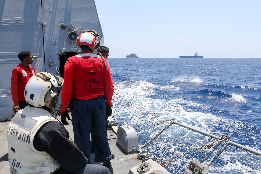 Sailors aboard the Arleigh Burke-class guided-missile destroyer USS Howard (DDG 083) prepare for a vertical replenishment-at-sea with the Lewis and Clark-class dry cargo USNS Wally Schirra (T-AKE-8)