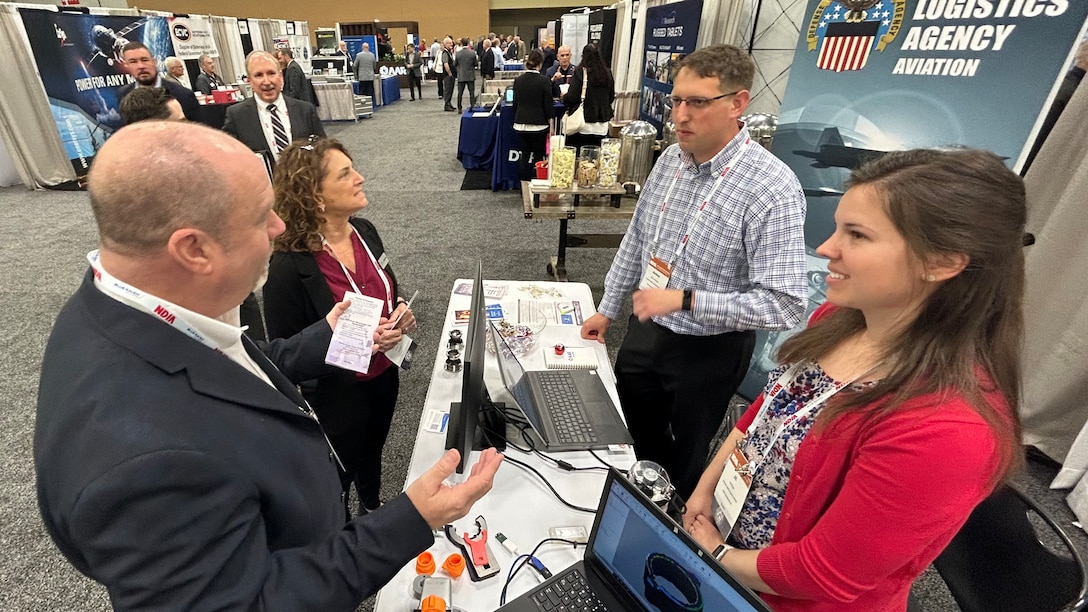 DLA Aviation employees talk to attendees at conference