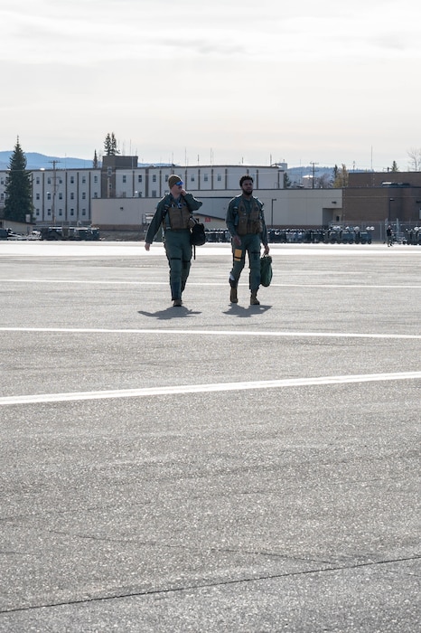 Two Airmen walk on the flightline.
