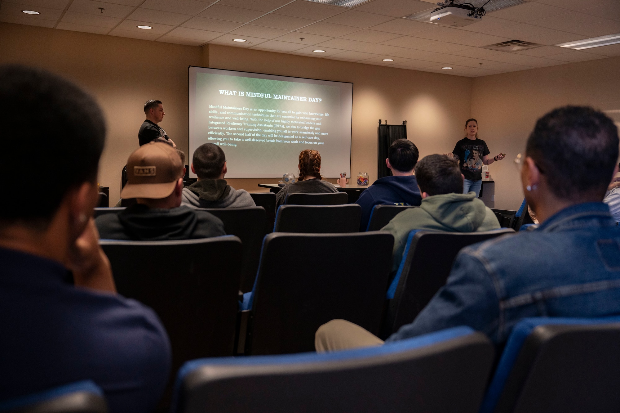 U.S. Air Force Tech. Sgt. Isaac Quintana, left, and Staff Sgt. Heather Tindell, integrated resiliency training assistants, explain the purpose of Mindful Maintainer Day at Nellis Air Force Base, Nevada, March 28, 2024.