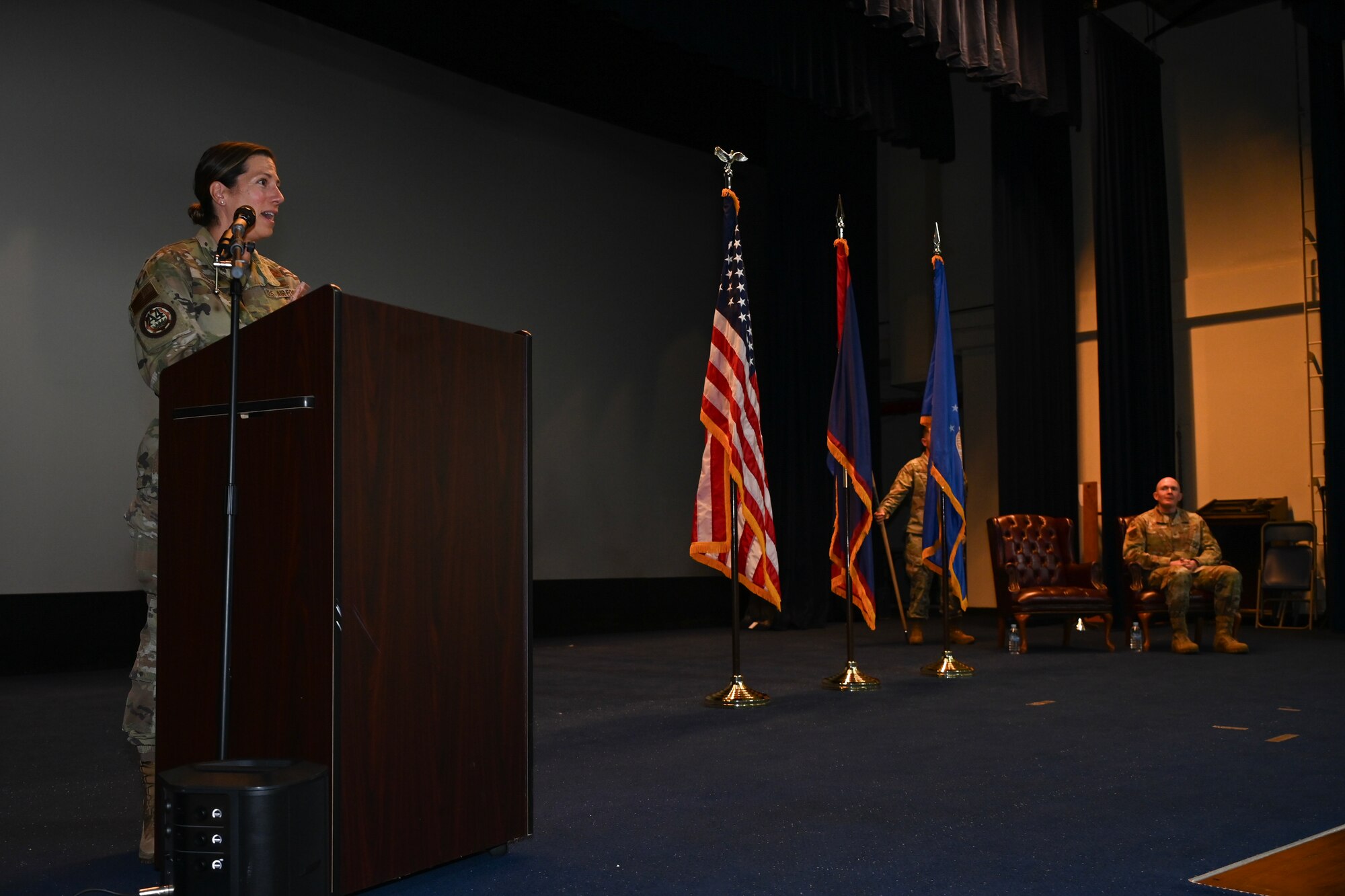 An Air Force commander stands on stage behind a podium and speaks to the audience.