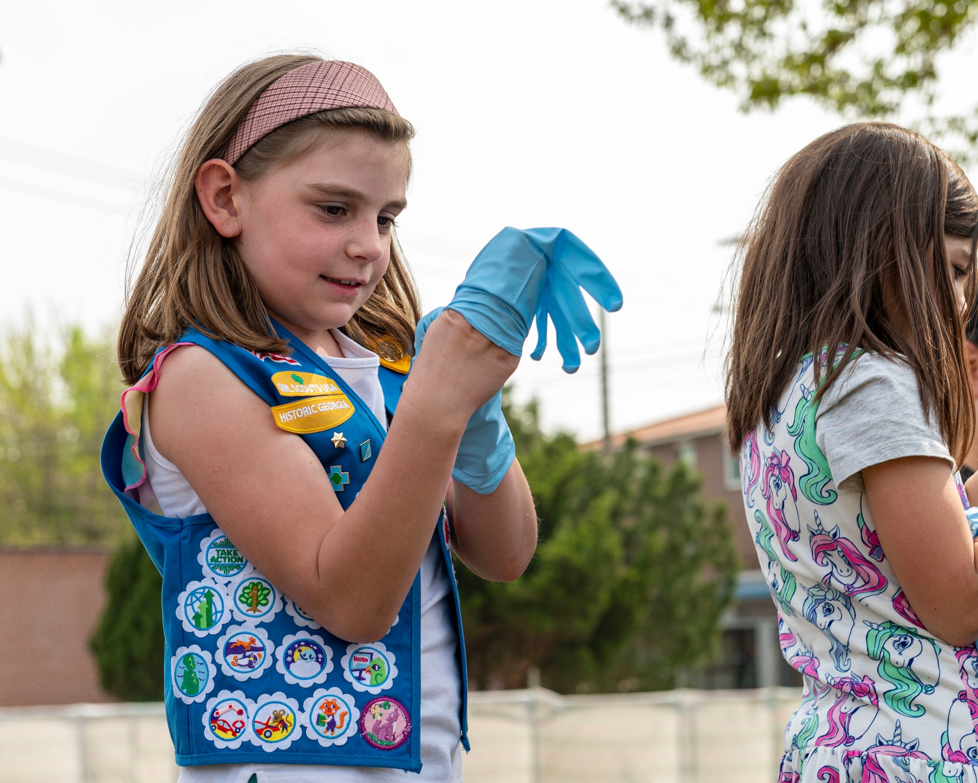 A member of Osan Girl Scouts puts on gloves in preparation to plant vegetation during an Earth Day planting event April 19, 2024 at Osan Air Base, Republic of Korea. The scouts helped the Osan Elementary School staff plant trees, bushes and flowers in celebration of Earth Day. Each April, the Department of the Air Force recognizes Earth Day to highlight the importance of protecting and stewarding the natural environment for the execution of the mission and the betterment of the planet. (U.S. Air Force photo by Staff Sgt. Aubree Owens)