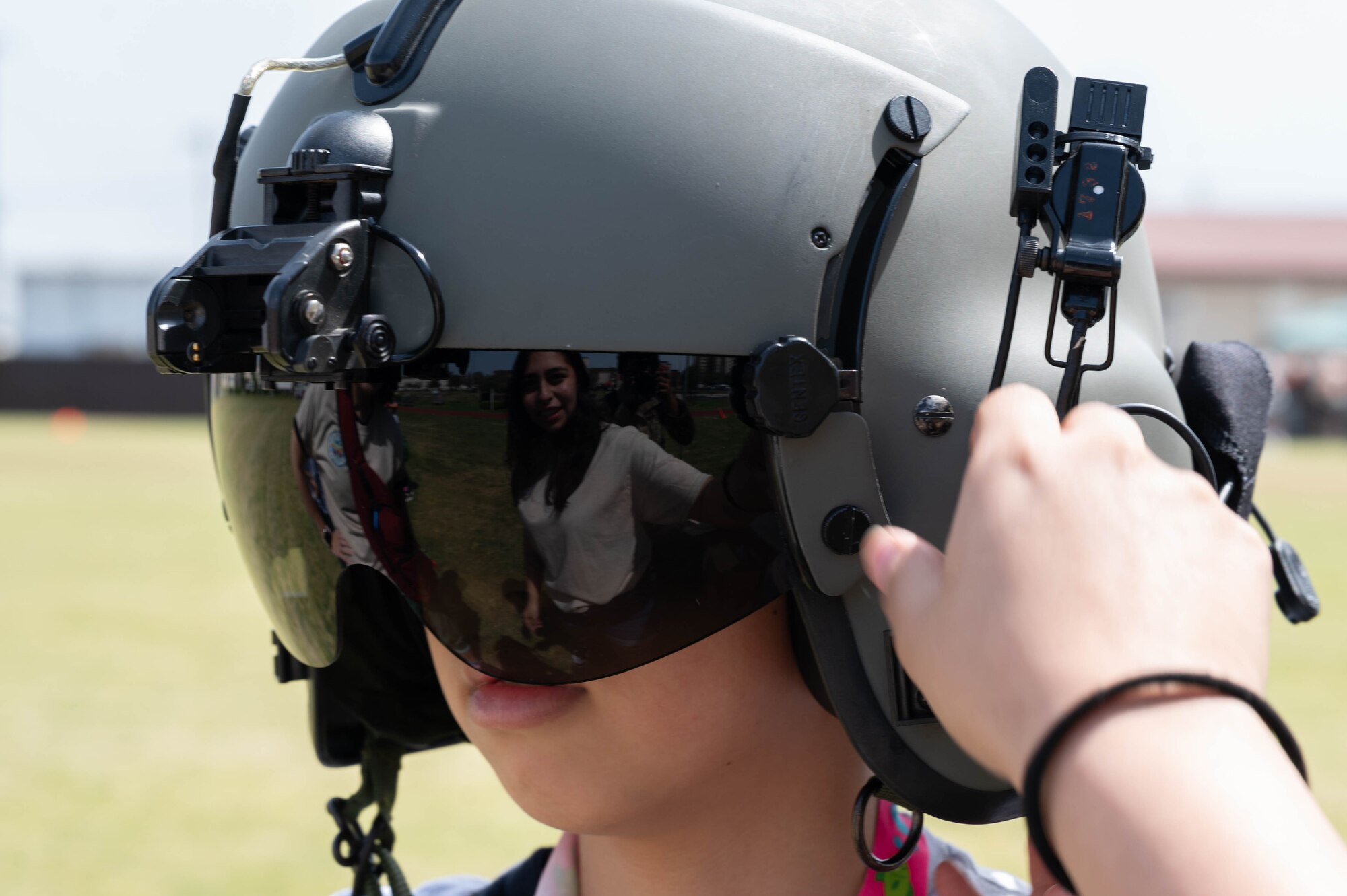 A volunteer helps a child try on a helmet.