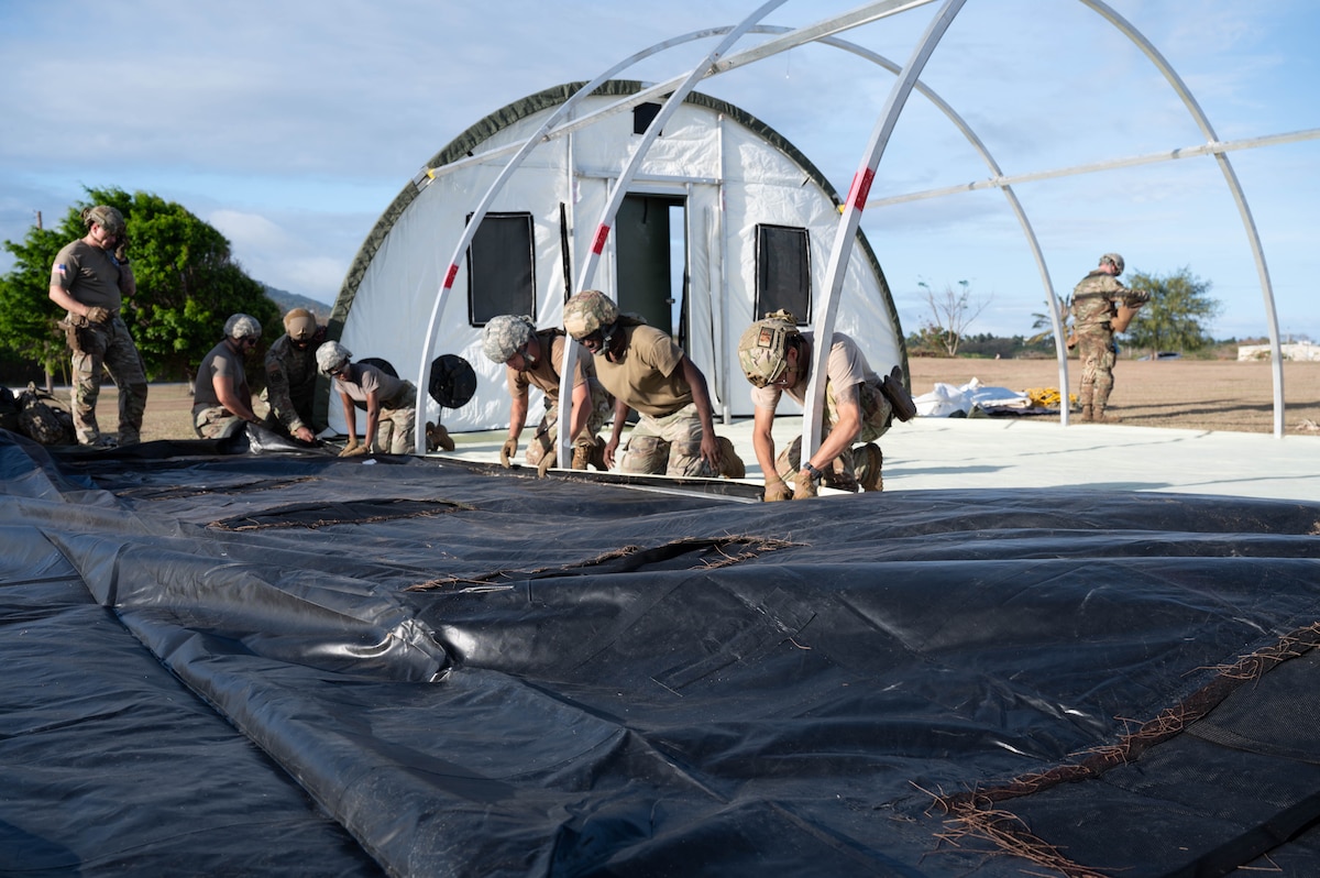 Airmen build a large tent together.