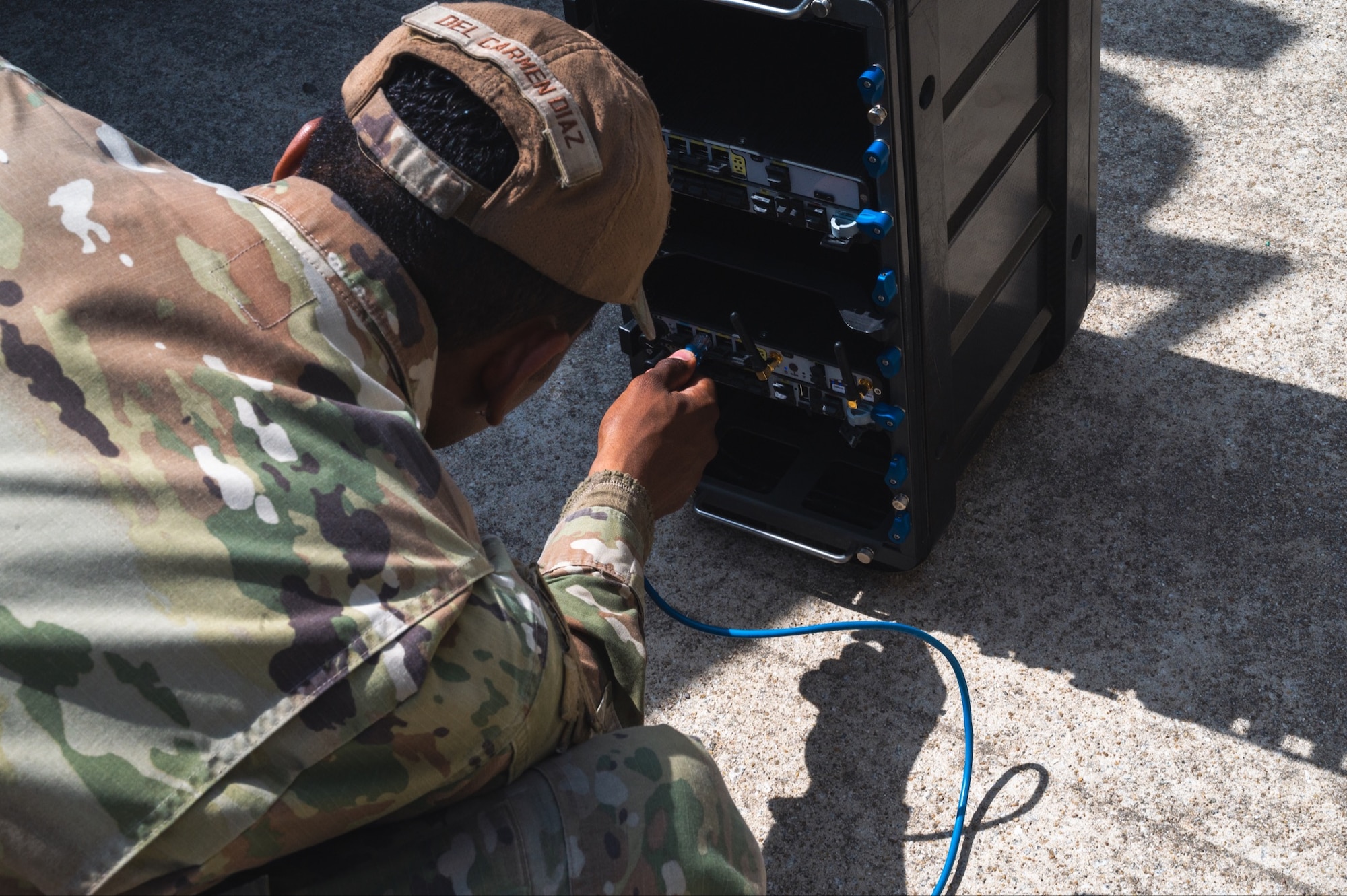 Airman 1st Class Luis Del Carmen Diaz lugs an ethernet cable into a server